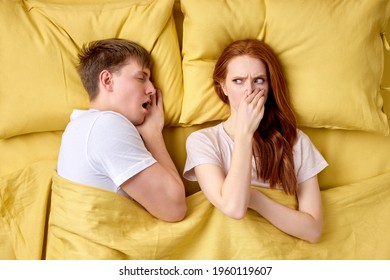 Woman Pinching Nose Due To Bad Breath By Male Mouth During Sleep