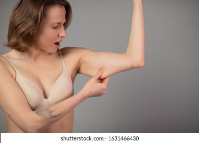 Woman Pinching Upper Arm Fat. Close up of Caucasian Female Hand Checking Flabby Skin. Body Control. Time to go on Diet and Weight Loss Concept
