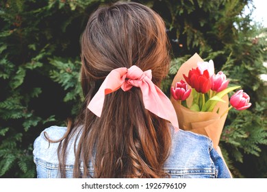 Woman with a pink bow in hair holding tulips, outdoors