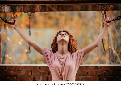 Woman in pink dress hanging with old chain when her head tilted back