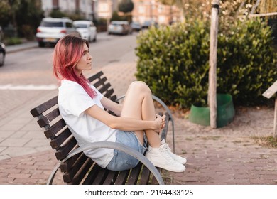 Woman with pink hair sitting on bench and smiling, walking in park, looking carefree and happy. Modern girl breathing fresh air on a walk, look free and joyful. - Powered by Shutterstock