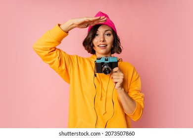 Woman In Pink Hat And  Orange Hoodie  With  Suprice Face  Using Photo Camera On Pink Bacground. 