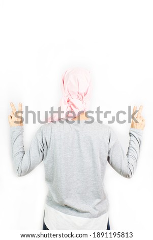 Woman with a pink headscarf for cancer performing the victory symbol. Concept of female cancer prevention