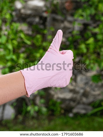 Woman in pink protective gloves outdoors. Female showing YES sign