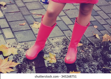 Woman With Pink Rain Boots Jumps Into A Puddle. Toned Image