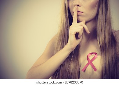 Woman Pink Ribbon On Chest With Finger On Lips, Hush Hand Gesture. Young Female Wearing Bra Showing Breast Cancer Awareness Symbol.