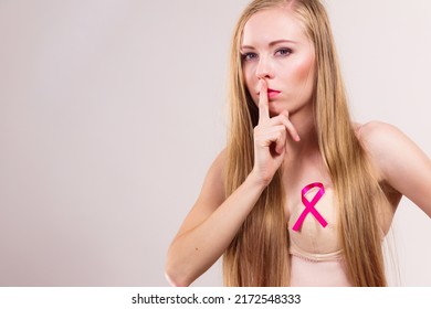 Woman Pink Ribbon On Chest With Finger On Lips, Hush Hand Gesture. Young Female Wearing Bra Showing Breast Cancer Awareness Symbol.