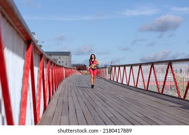 A Woman In A Pink Sweat Suit Runs Across The Bridge.