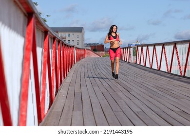 A Woman In A Pink Sweat Suit Runs Across The Bridge.