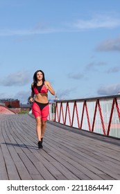 A Woman In A Pink Sweat Suit Runs Across The Bridge.