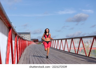 A Woman In A Pink Sweat Suit Runs Across The Bridge.