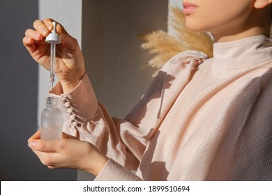 Woman In Pink Vintage Blouse Holding Serum Glass Bottle With Pipette. Hyaluronic Acid, Retinol. Trendy Colors. Skin Care Routine Concept. Hydrating Facial Moisturizer