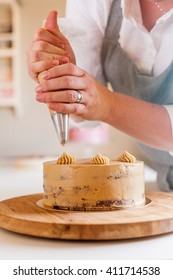 Woman Piping Decoration On A Cake