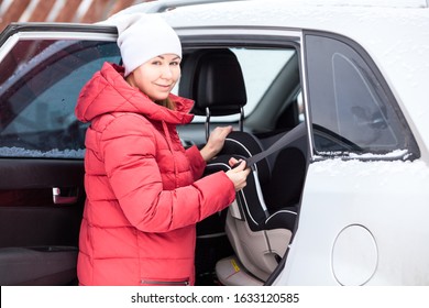 Woman Placing Baby Safety Seat In The Car, Fastening With Belt. Rear Seat Of Suv