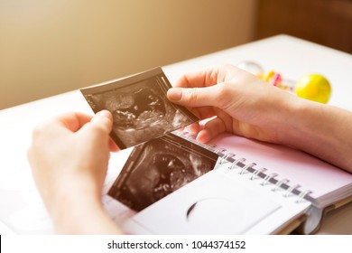 Woman Placing Baby's Sonogram Into Baby's First Year Memory Book