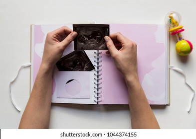 Woman Placing Baby's Sonogram Into Baby's First Year Memory Book