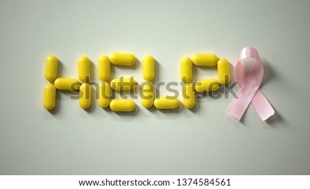 Woman placing pink ribbon near help word made of pills on table, breast cancer
