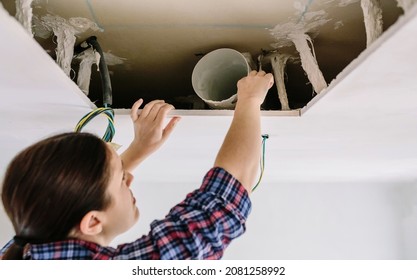 Woman Placing Tube For Kitchen Hood Installation On Kitchen Ceiling