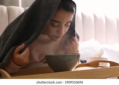 Woman with plaid doing inhalation above bowl indoors - Shutterstock ID 1909510696
