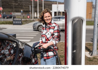Woman in a plaid shirt charging an electric car