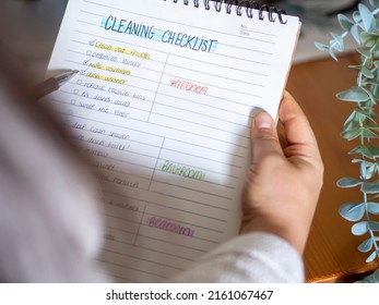 Woman planning a spring cleaning checklist routine for the household. Handwriting To-do list for organizing house cleaning with checkmarks for motivation. Tidy and domestic life.