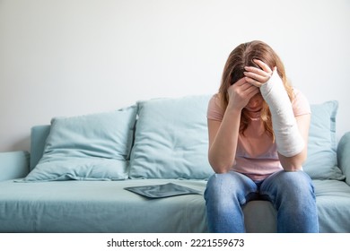 A Woman With A Plaster Cast On Her Arm Holds Her Head.