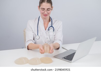 Woman Plastic Surgeon Demonstrating Breast Implants At Her Desk. 