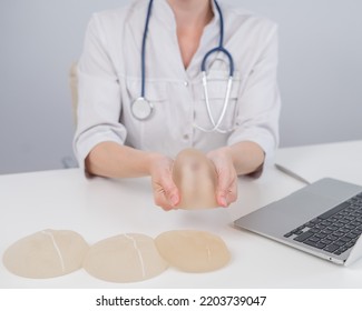 Woman Plastic Surgeon Demonstrating Breast Implants At Her Desk. 