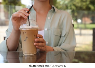 Woman With Plastic Takeaway Cup Of Delicious Iced Coffee At Table In Outdoor Cafe, Closeup. Space For Text