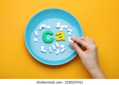 Woman, plate with pills and calcium symbol made of colorful letters on orange background, top view