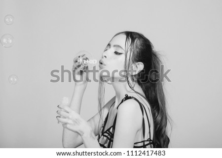 Woman play with soap balloon. Bubble blower in hand of fashion model. Fun and joy. Girl with glamour makeup and hair. Beauty and fashion.