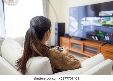 Woman play video game and sit on sofa at home - Powered by Shutterstock