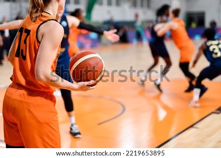 Woman player keeps the ball during basketball match.