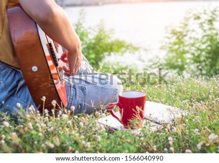 Woman is playing acoustic guitar in park.