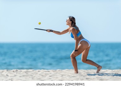 Woman playing beach tennis on a beach. Professional sport concept. Horizontal sport theme poster, greeting cards, headers, website and app - Powered by Shutterstock