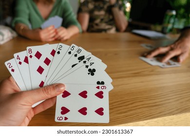 Woman playing with cards with friends close up .