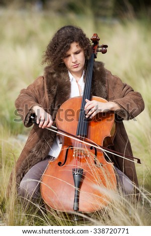 woman playing the cello between fields