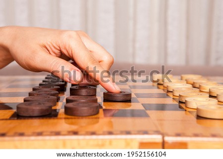 Woman playing  checkers game makes his move. 
