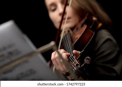 Woman Playing A Classical Violin During A Recital In A Close Up Cropped Low Angle With Focus To Her Fingers On The Strings