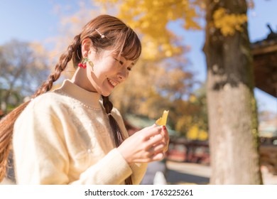 
A Woman Playing With Fallen Leaves Of Ginkgo