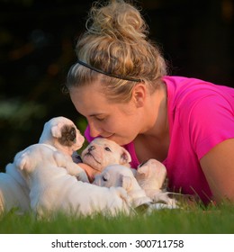 Woman Playing In The Grass With Litter Of Puppies