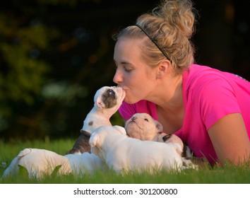 Woman Playing In The Grass With Litter Of Puppies