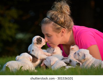 Woman Playing In The Grass With Litter Of Puppies