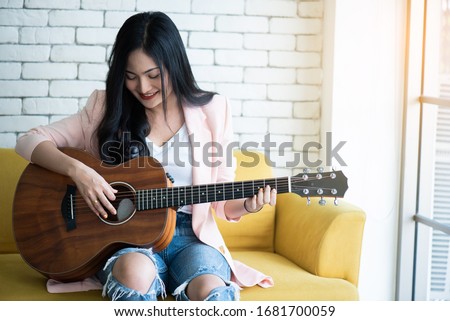 woman playing guitar on sofa .