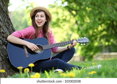 Woman Playing Guitar In Park