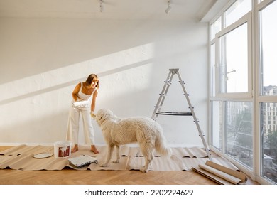 Woman Playing With Her Dog While Making Repairment In Newly Purchased Apartment. Repair And House Renovation Concept, Leisure Time