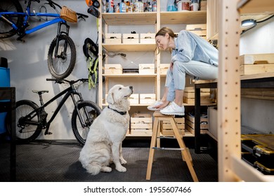 Woman Playing With Her Huge White Dog In The Workshop Or Garage At Home