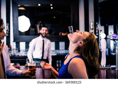 Woman playing with her shot in a bar with friends