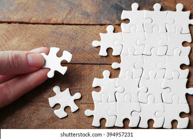 Woman playing with jigsaw puzzle on wooden table