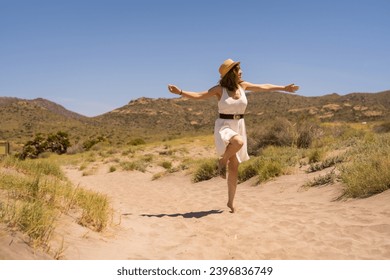 Woman playing and jumping along a sandy path in Cabo de Gata, Spain - Powered by Shutterstock